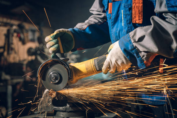 istock Locksmith in special clothes and goggles works in production. Metal processing with angle grinder. Sparks in metalworking 1290163043