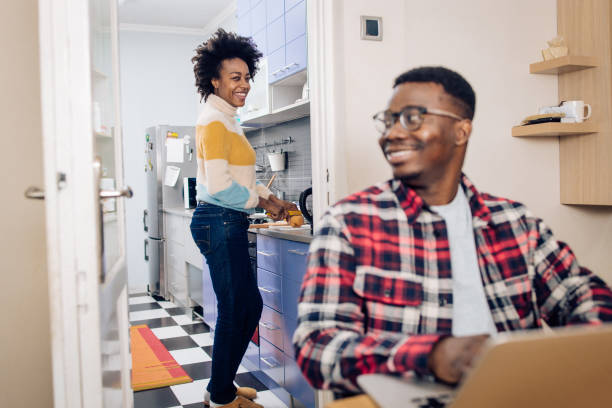 istock African-American man working while his girlfriend preparing food in the kitchen 1290165891