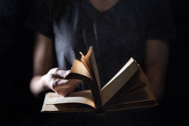 istock Hands hold Vintage open Book Glows on black background. Concept of reading, knowledge and open mind 1290166028