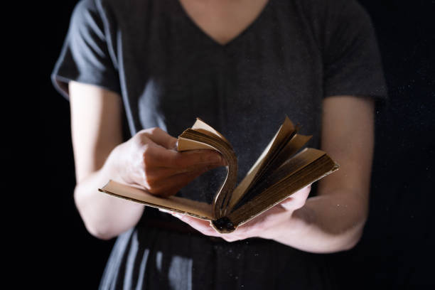 istock Hands hold Vintage open Book Glows on black background. Concept of reading, knowledge and open mind 1290166793