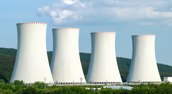 Nuclear power plant. Cooling towers on the background of blue sky and mountains.