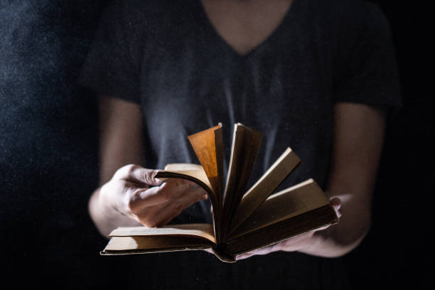 istock Hands hold Vintage open Book Glows on black background. Concept of reading, knowledge and open mind 1290167767