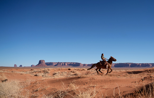 Navajo young woman galloping fast in Monument Valley Arizona - USA