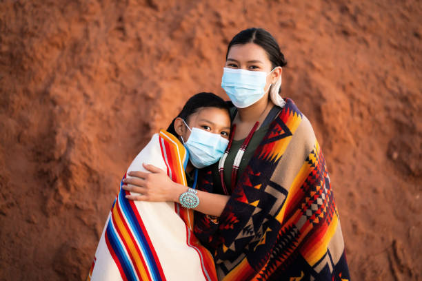 native indische amerikaner schwestern mit gesichtsmaske vor trösten einander während covid-19 quarantäne - navajo american culture indigenous culture women stock-fotos und bilder