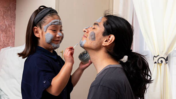 Young man with a girl sitting on a bed talking and laughing, while putting on a face cream, playing in a spa at home Young man with a girl sitting on a bed talking and laughing, while putting on a face cream, playing in a spa at home beautiful mexican girls stock pictures, royalty-free photos & images