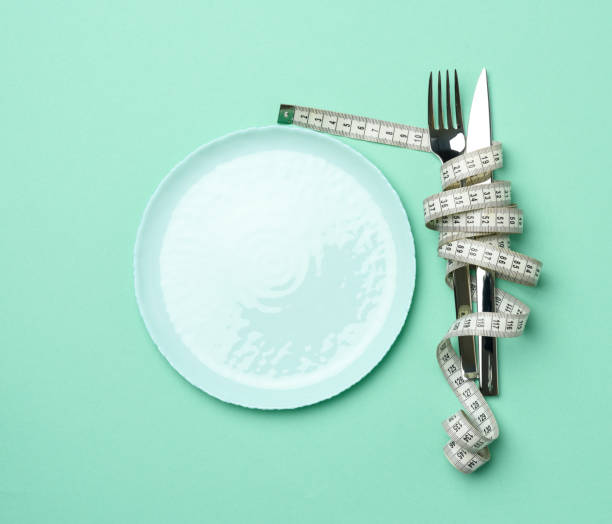 istock empty round plate and fork and knife wrapped in white measuring tape 1290173567