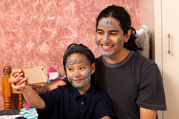 istock young man with a little girl, wearing facials taking a selfie, while smiling 1290174394