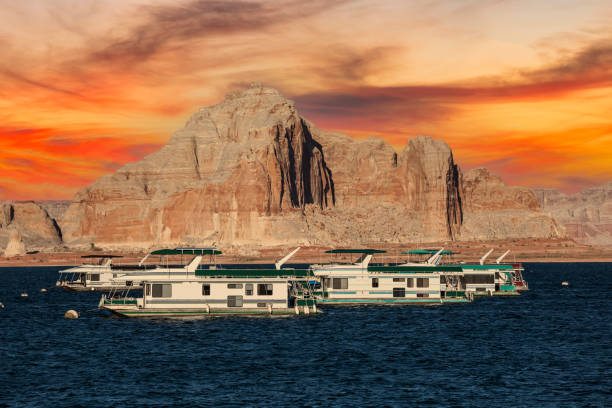 Lake Powell Houseboats and Peaks with Sunset Sky Desert sandstone peaks and houseboats with sunset sky at Lake Powell in the Glen Canyon National Recreation Area. glen canyon stock pictures, royalty-free photos & images