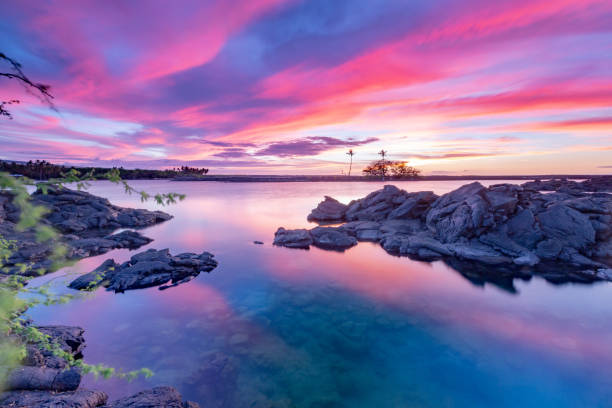 розовый и фиолетовый закат над заливом кихоло, гавайи - coral water sunset usa стоковые фото и изображения
