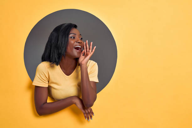 Portrait of pretty responsible woman with modern hairdo holding palm near wide open mouth calling someone yelling information announcement loudly isolated on grey circle hole in yellow background. Portrait of pretty responsible woman with modern hairdo holding palm near wide open mouth calling someone yelling information announcement loudly isolated on grey circle hole in yellow background. showing off stock pictures, royalty-free photos & images