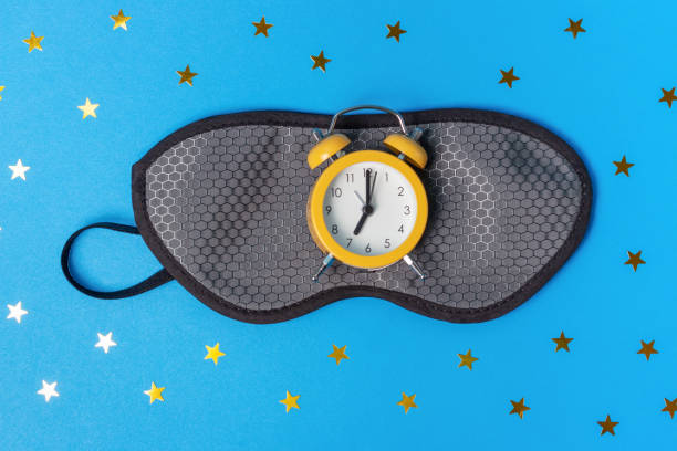 istock Sleep mask and alarm clock on blue background top view. 1290182265