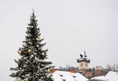Beautiful Christmas tree and famous Clock Tower on Schlossberg hill, view from the main square Hauptplatz , in winter, in the city center of Graz, Styria region, Austria. Selective focus
