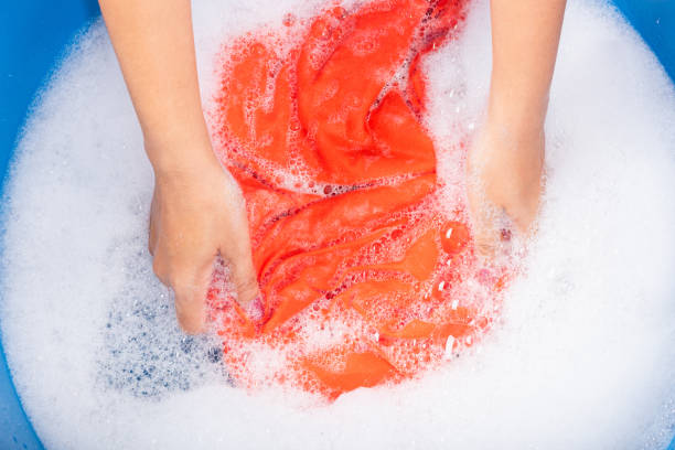istock Woman use hands washing color clothes in basin 1290189182