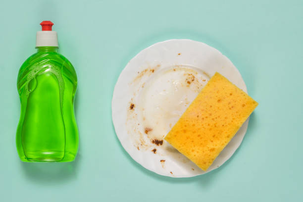 istock Detergent and a dirty plate with a foam sponge on a blue background. 1290192699