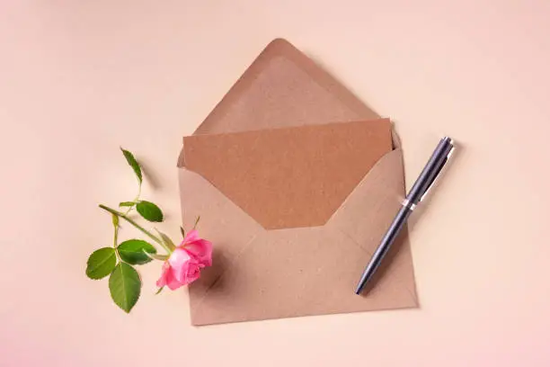 Photo of Invitation or greeting card mock up in a craft envelope, overhead flatlay shot