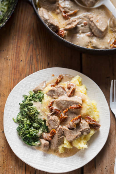 istock Pork loin with sun dried tomatoes in cream sauce with mashed potatoes and spinach 1290212854