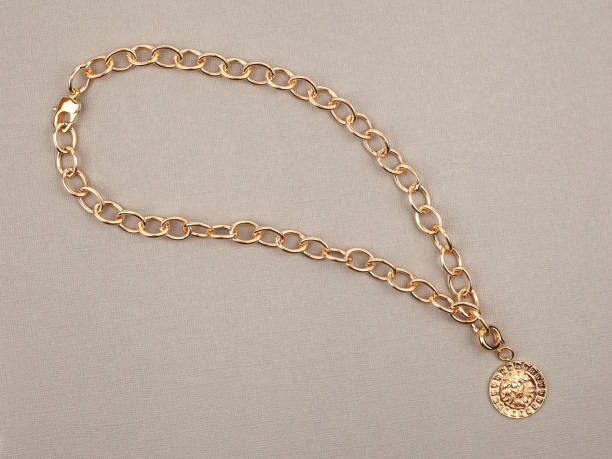 istock Golden pendant with chain on beige textured background 1290214671