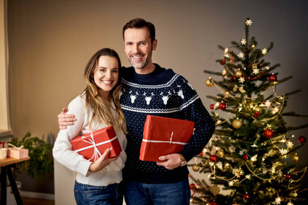 istock Smiling couple holding Christmas presents at home 1290216146