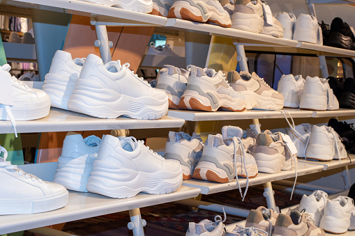 Side view of the shelves of a shoe store with many sales of sneakers. Close up image of some sneakers in a store. Business concept