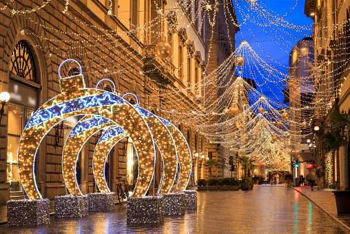 Christmas decorations and lights in main street in Florence, italy at night after rain