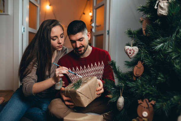 istock couple decorating christmas tree and preparing presents 1290218472