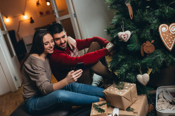 istock couple decorating christmas tree and preparing presents 1290218484