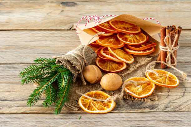istock Christmas composition with spruce tree branches, cinnamon sticks and garland made of dried slices of oranges on wooden background. Rustic style. 1290219627