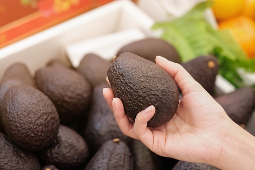 Woman shopping for avocado in supermarkets