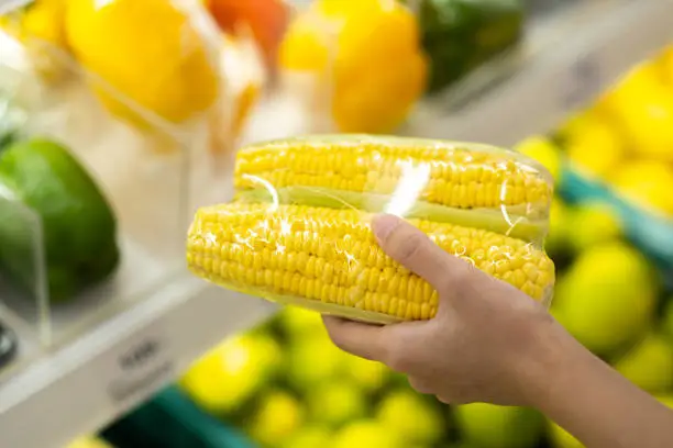 Woman shopping for raw corn in supermarkets