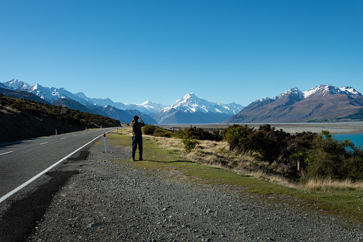 Tourist taking mobile phone photos of Mt Cook on the side of the road