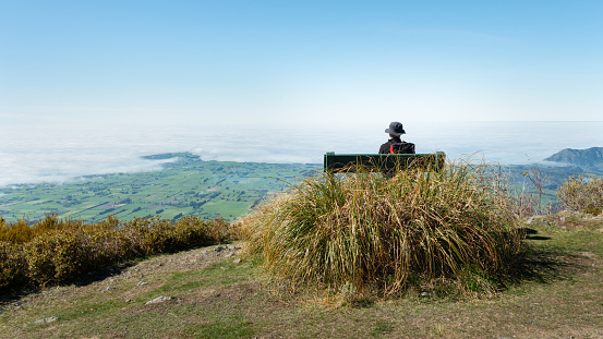 A backpacker sitting on the bench and admiring the views of Kaikoura peninsula from Mt Fyffe track, South Island, New Zealand