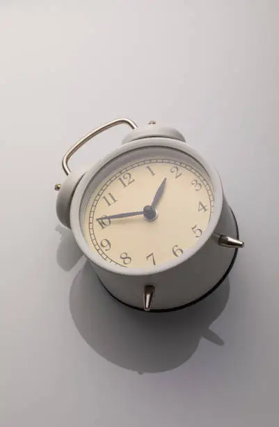 Photo of Beige iron alarm clock on neutral background