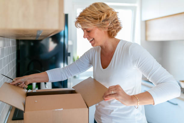 istock Smiling woman with kitchen knife looking into a cardboard box 1290226760