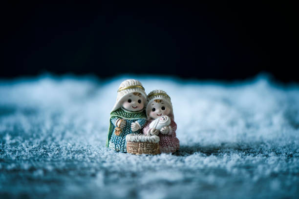 the holy family, the child jesus, the virgin mary and saint joseph, on the snow against a black background with some blank space on top