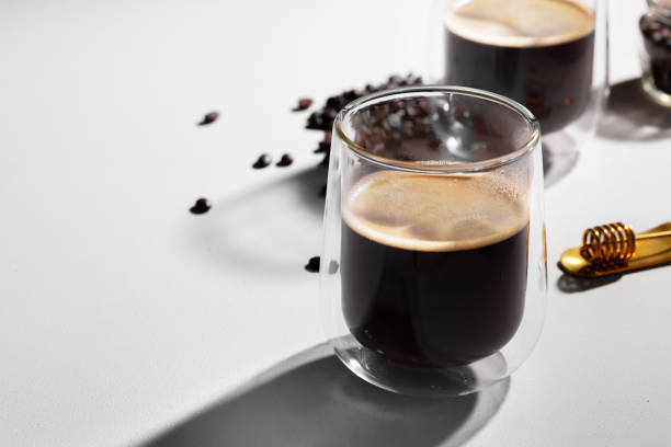 istock Glass cups of coffee and coffee beans on white table 1290228773