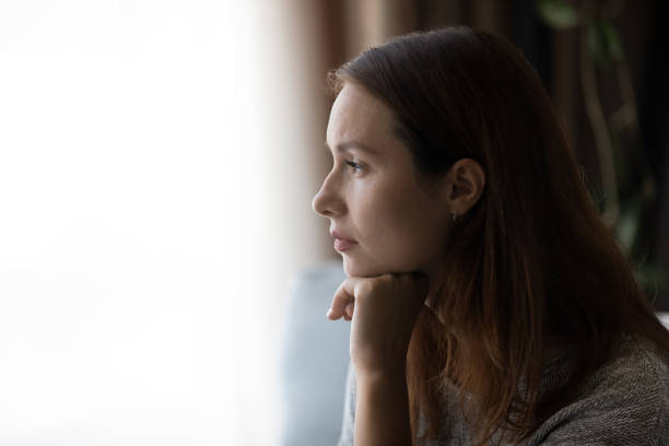 istock Pensive young woman looking in distance at window. 1290230567