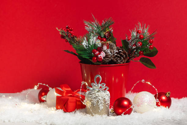 istock Christmas card composition with snow and Christmas tree branches decoration and present boxes on the red background 1290232133
