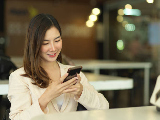 istock Businesswoman relaxing with smartphone while sitting in cafeteria 1290233016