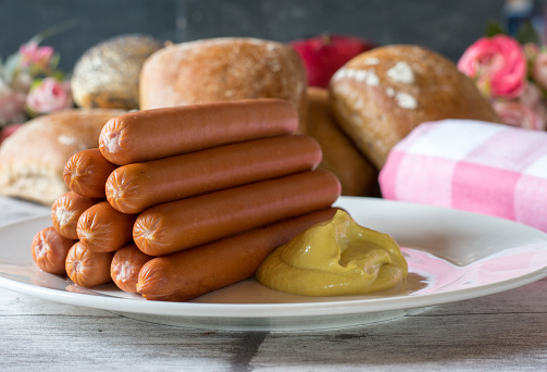 traditional german fast food recipe with natural ingredients. Hot dogs or wiener würstchen with mustard and rolls served on a plate. Close up view
