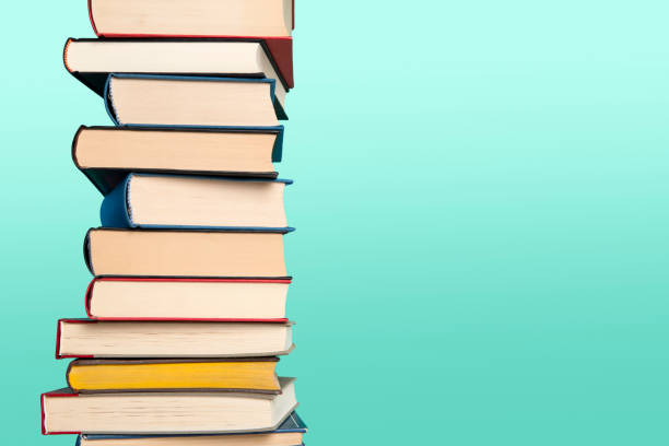 istock Pile of books stacked on a blue background with space for copy 1290234577