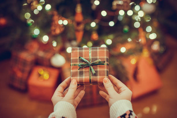 Woman putting gift box under christmas tree. Presents for family.