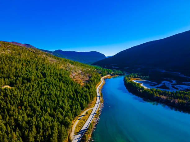 istock Highway running through a river valley in the mountains with pristine clear blue water and frozen plains in the shadow side of the valley. 1290238713