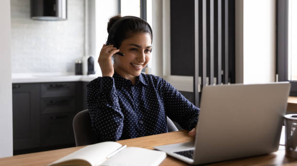 istock Active young indian woman taking part in videoconference using headphones 1290242634
