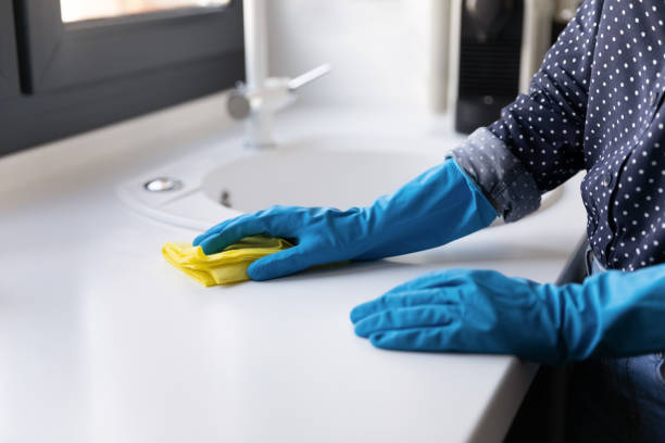 istock Female hands in rubber gloves cleaning kitchen counter with rag 1290242746