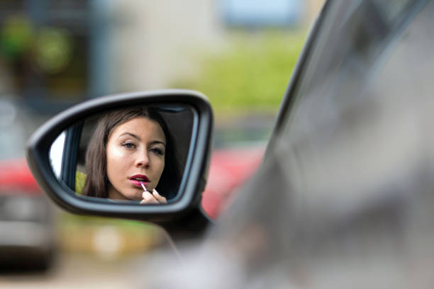 istock teenager driver applying lipstick using rear mirror in a car 1290244866