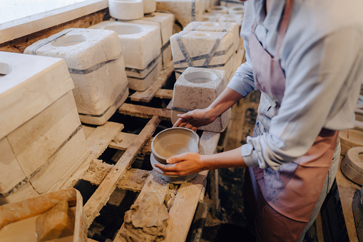 Photo of a young woman, a sculptor, making a pottery in her art workshop