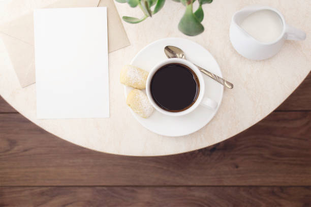 istock A cup of coffee with cookies, a silver spoon, milk, an empty letterhead with an envelope on a marble table in a cafe. Top view 1290246053