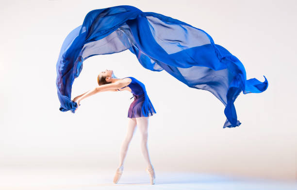istock Elegant ballerina in pointes dances with developing blue cloth on white background 1290246187