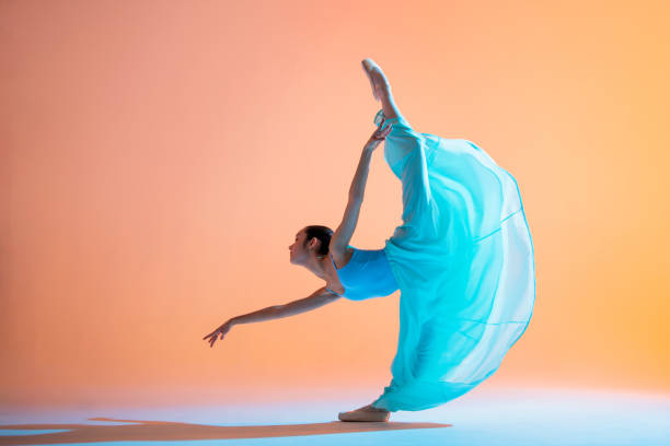 istock Ballerina in a light blue dress is dancing on colored background with pink backlight 1290246211