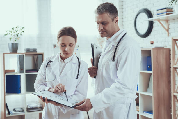 istock Male and female doctors with stethoscopes in office. Doctors are comparing notes. 1290247301